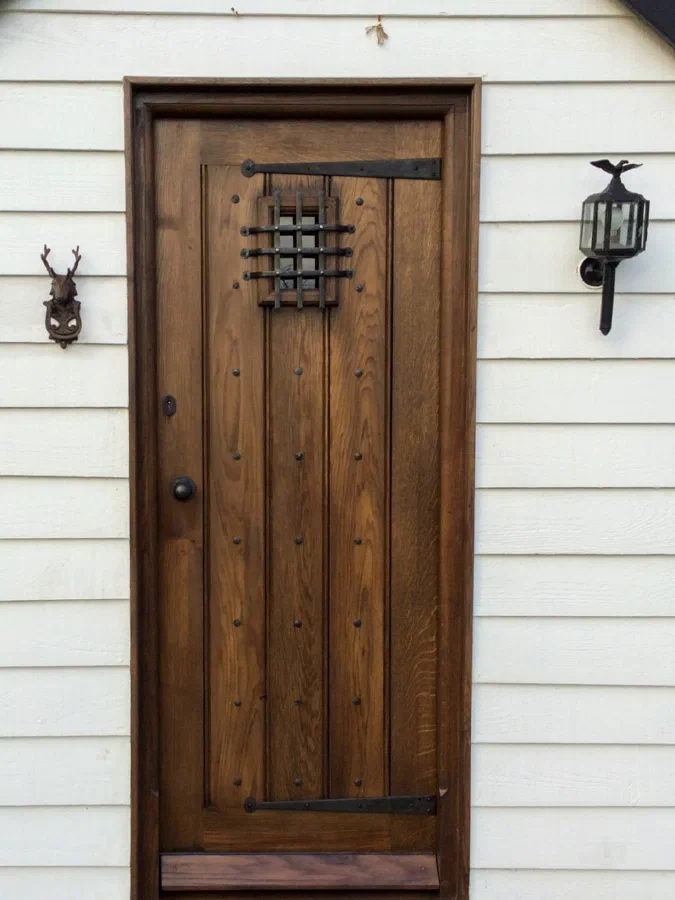 Dark-finished framed plank door set into a weatherboarded wall