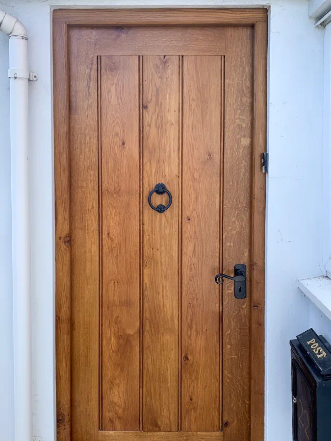 Solid European oak framed plank external door in a rendered opening