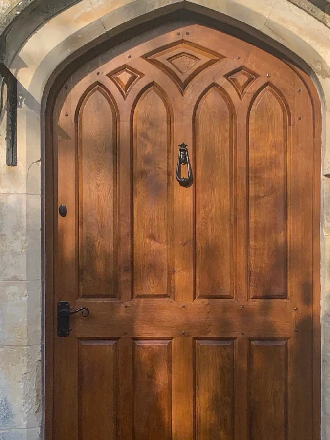 Arched oak front door with pointed Gothic panels in a stone doorway