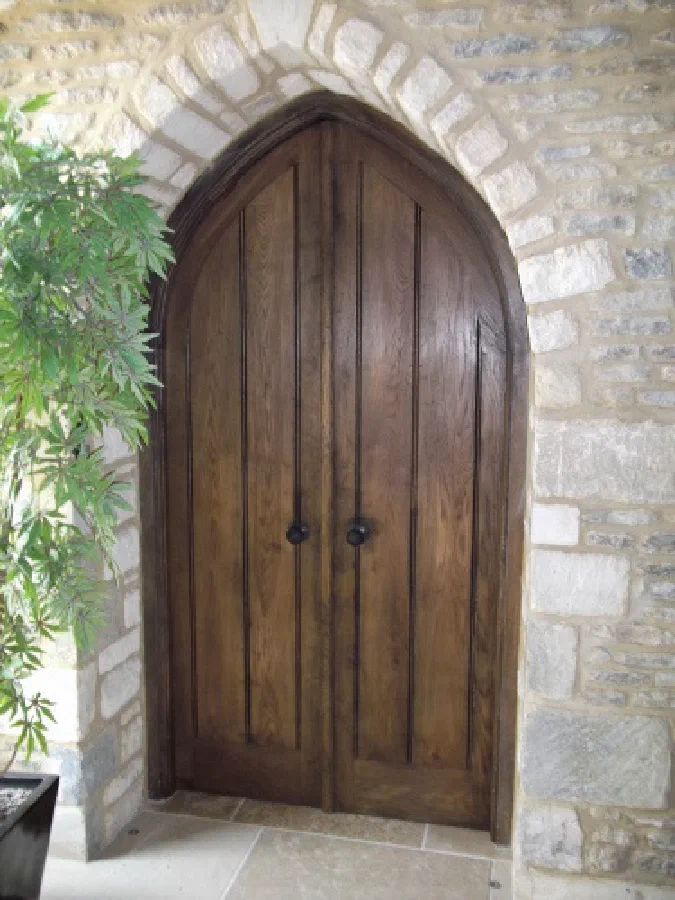 Pair of oak doors with ring handles beneath a pointed stone arch