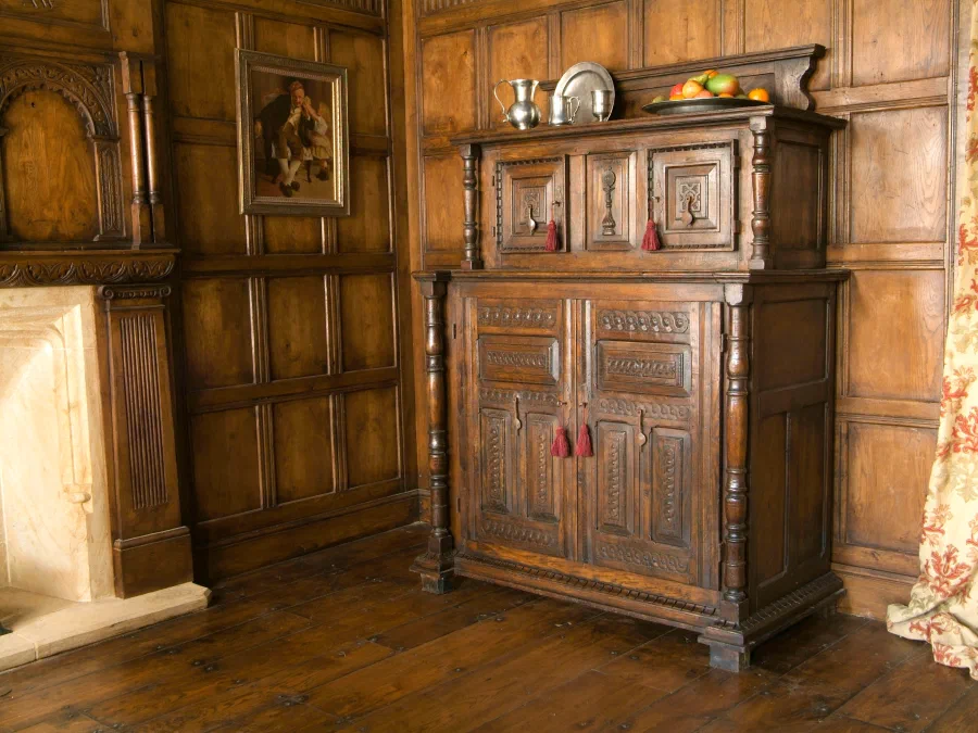Carved oak court cupboard against oak panelling