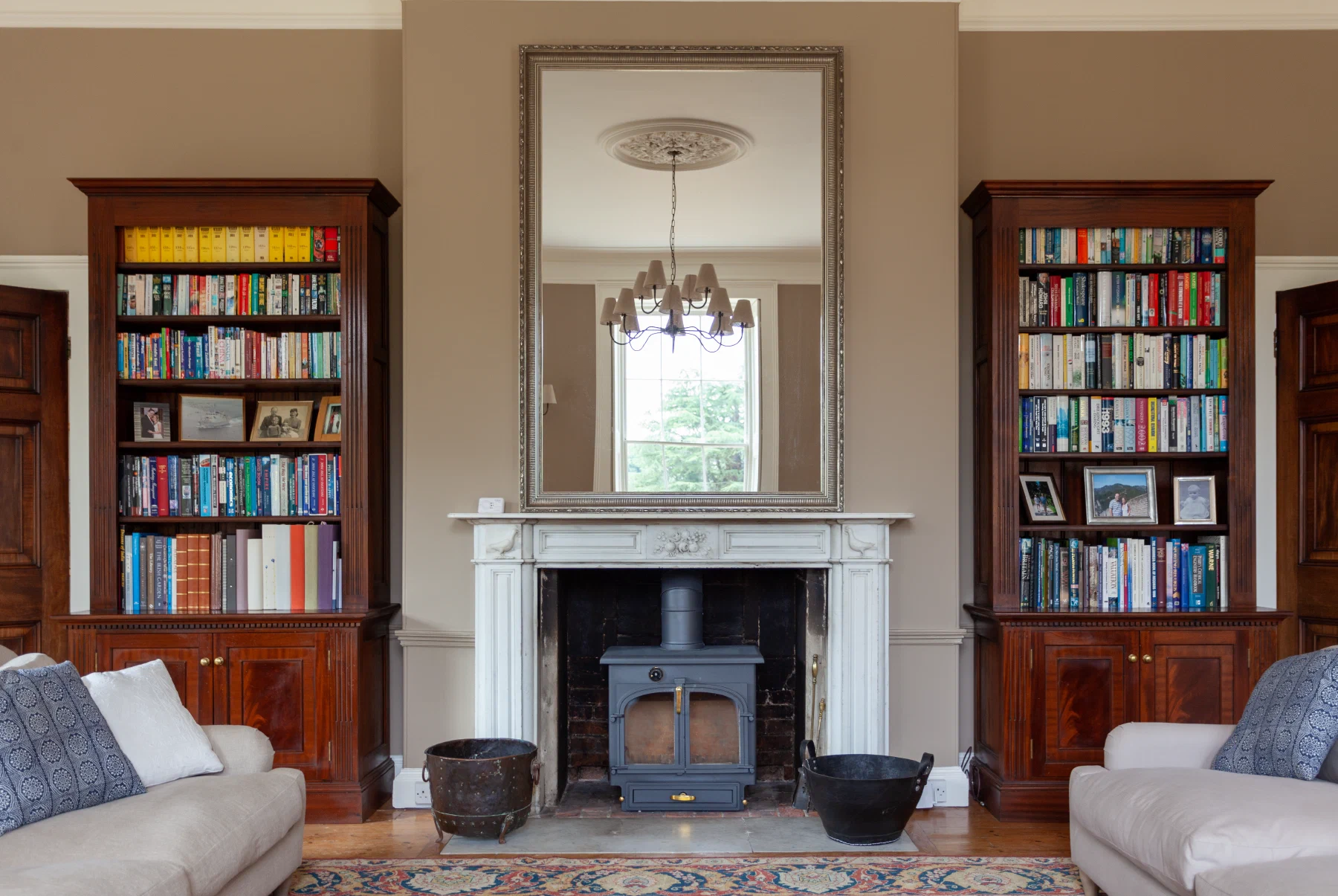 Pair of mahogany bookcases with lower cupboards either side of a fireplace