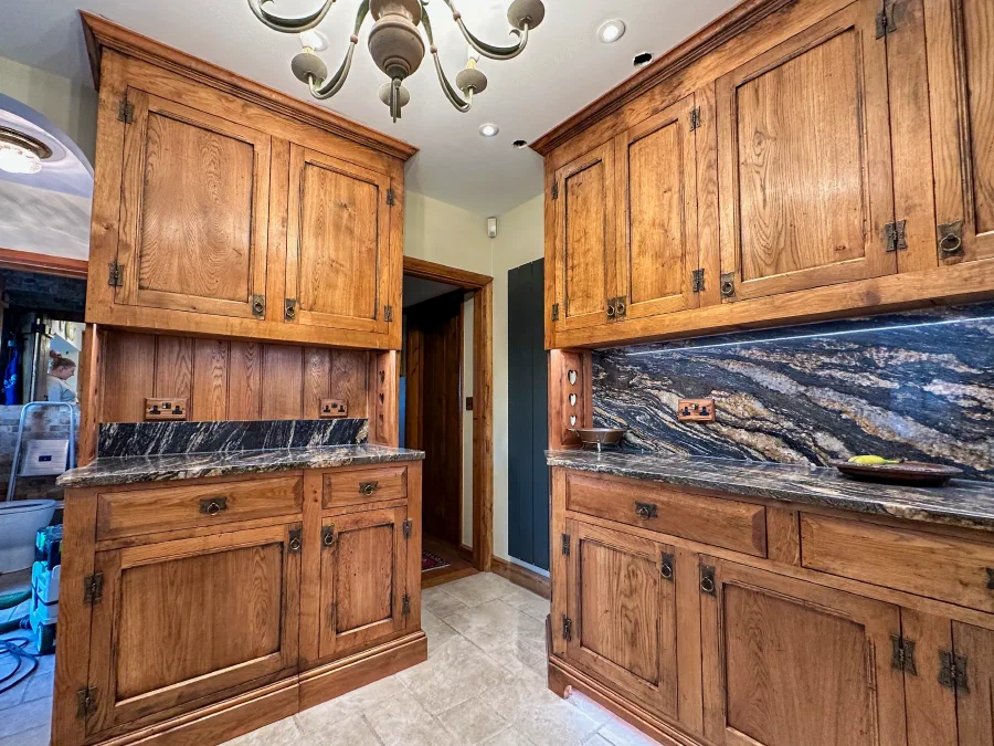 Oak kitchen cabinets with a stone splashback either side of a doorway