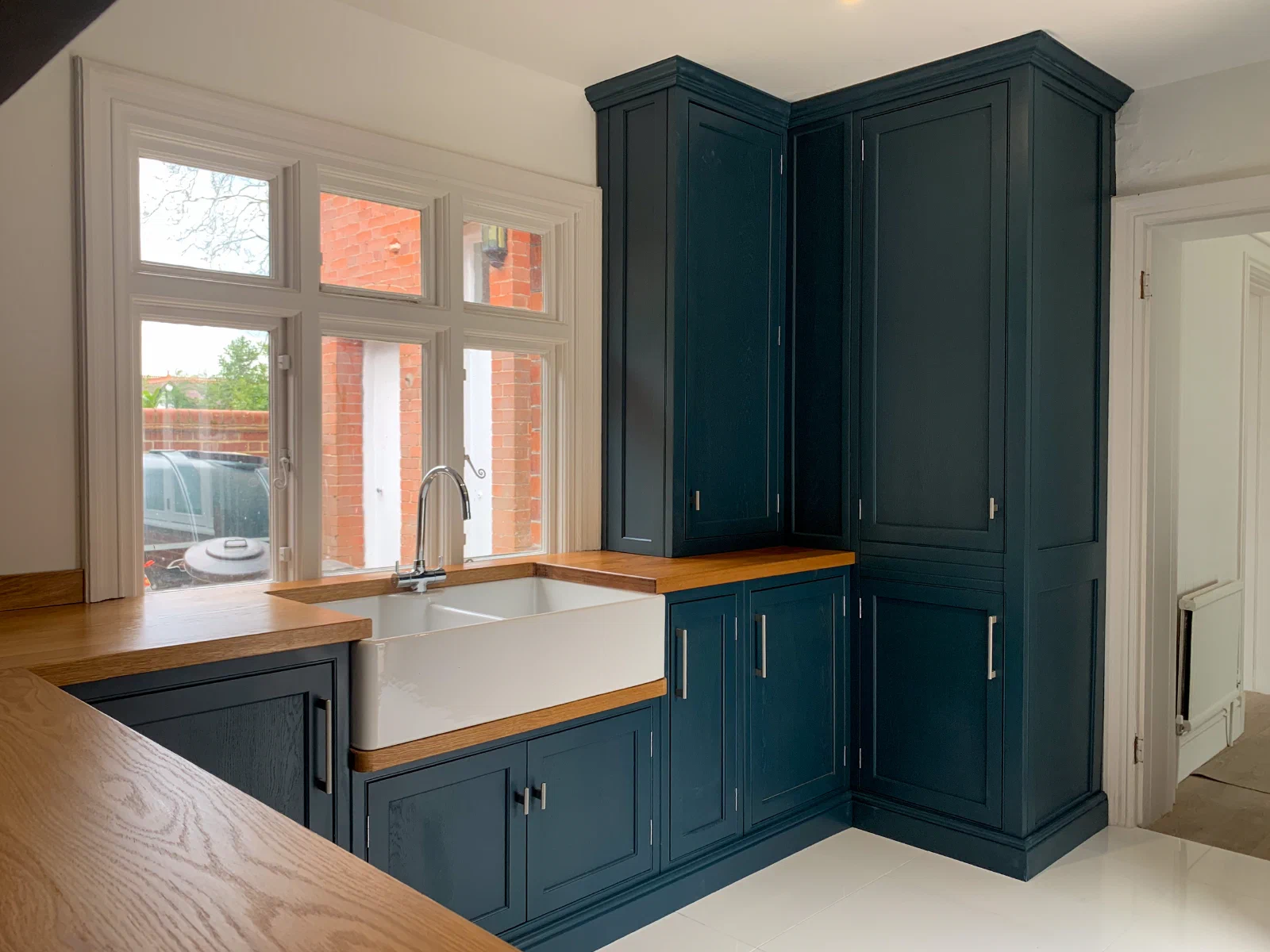 Deep blue painted cabinetry arranged around a sink and tall cupboard