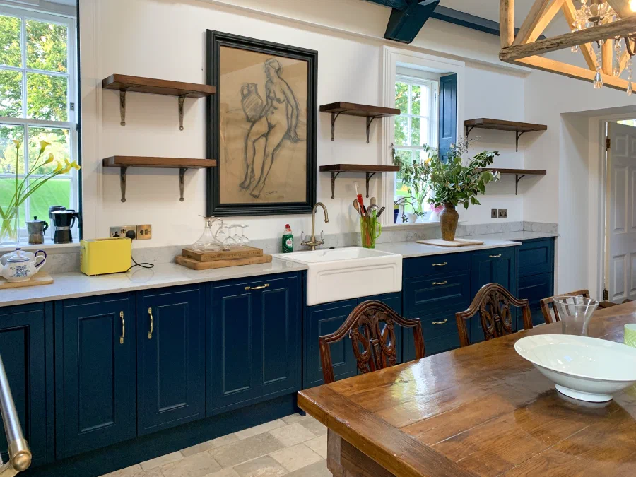 Painted kitchen cabinets and open wall shelves beside a dining table