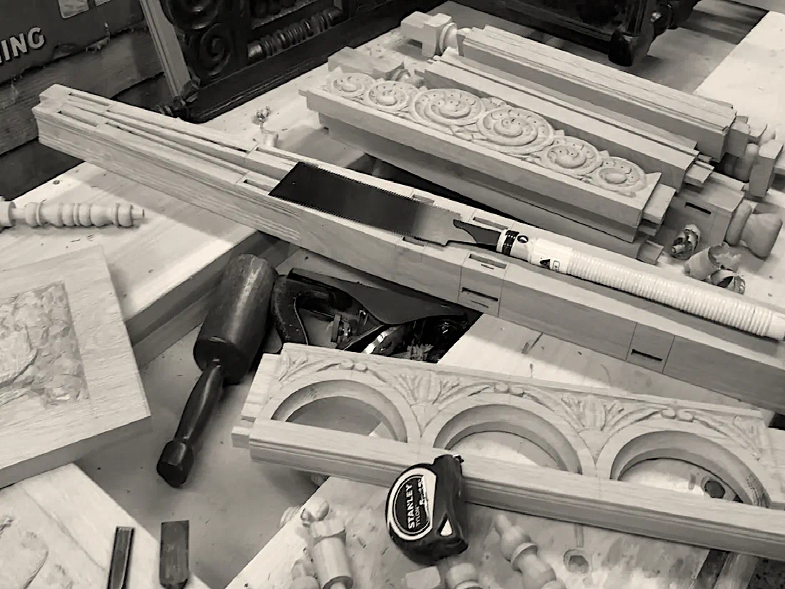 Hand tools and carved timber components on a workshop bench