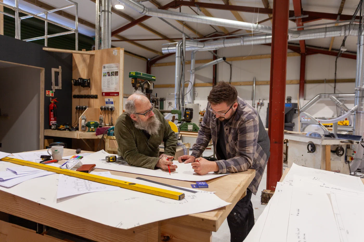 Two craftspeople resolving details on full-size workshop drawings