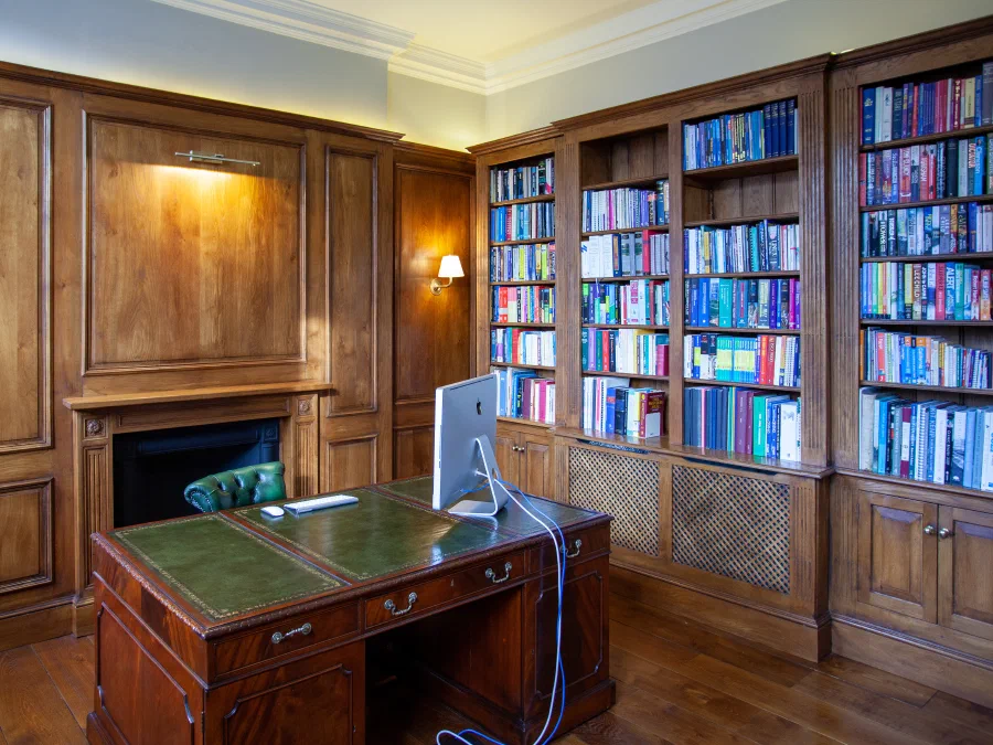 Oak panelled study with a fireplace and fitted bookcases