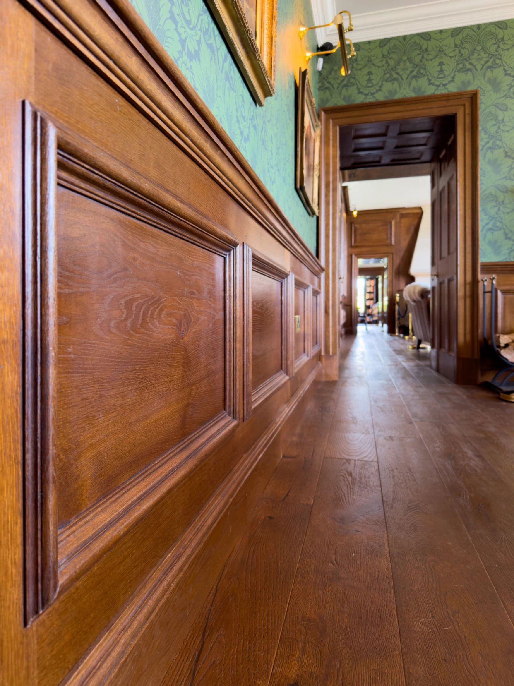 Close view of oak dado panelling with moulded panels and dado rail along a hallway