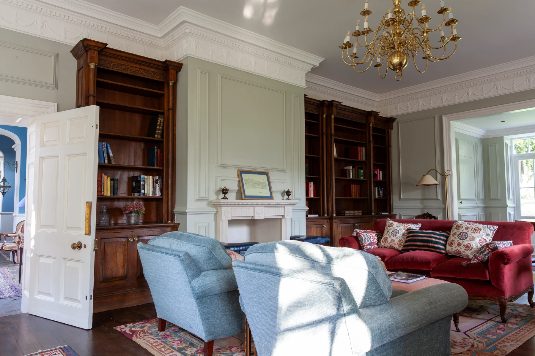 Painted Georgian panelling with oak bookcases either side of a chimneypiece at Alderwick House