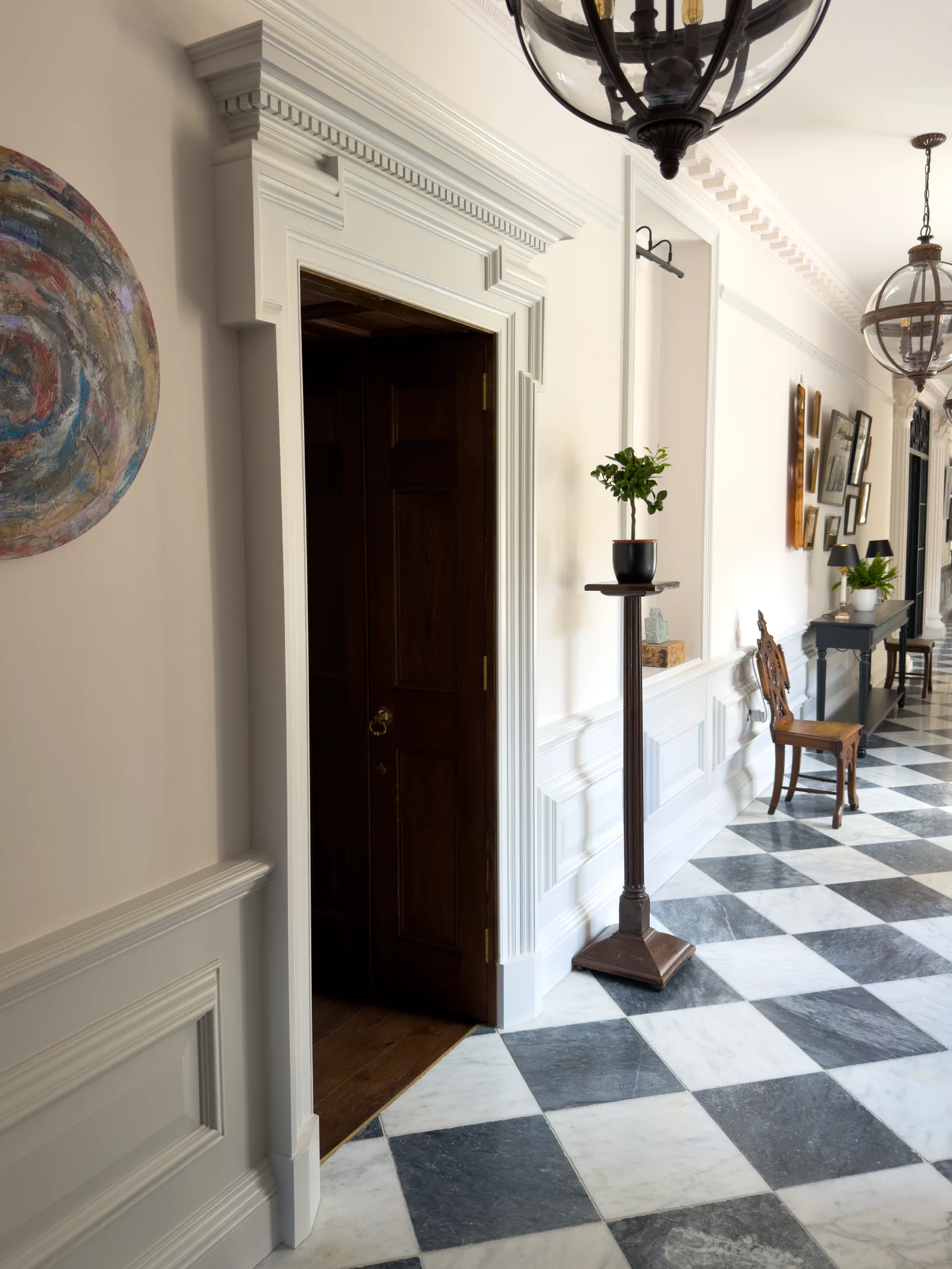 Painted pedimented doorcase with a dentil cornice and dado panelling in a stone-floored hall