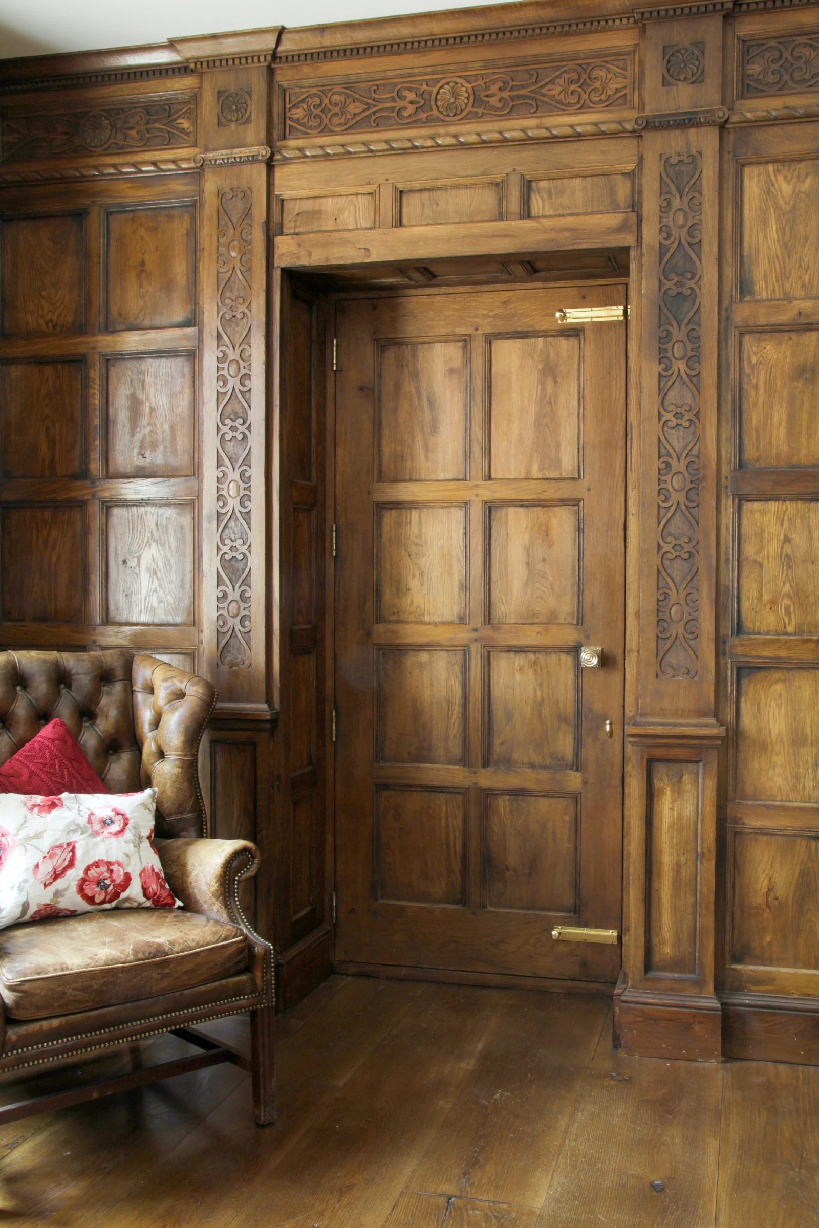 Finished oak panelling with an integrated panelled door and carved detail