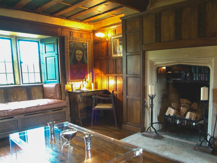 Oak panelled room with a fireplace and deep window seat