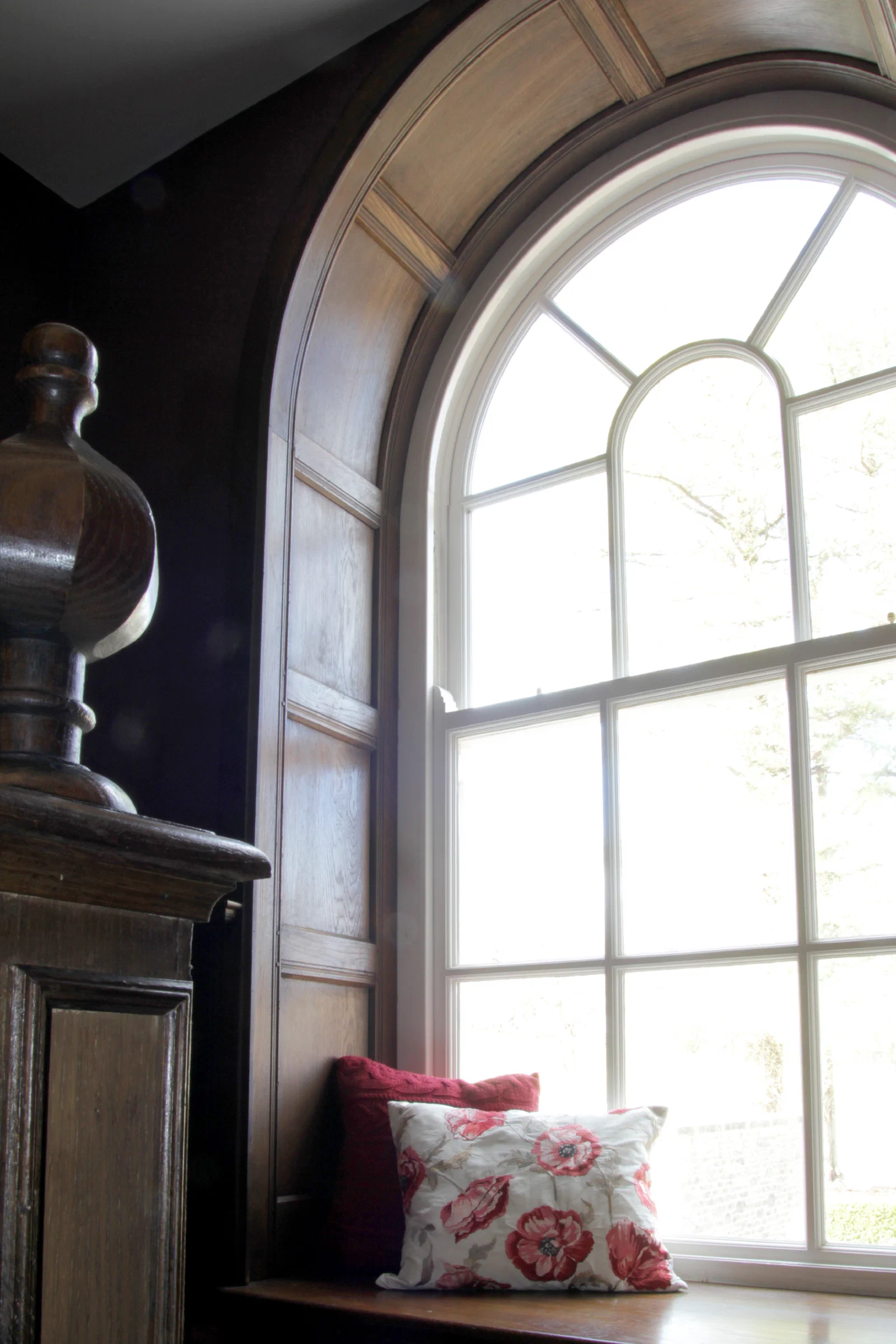 Oak panelling shaped around an arched window and fitted window seat