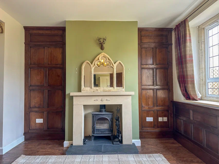 Oak panelling and fitted doors arranged around a stone fireplace