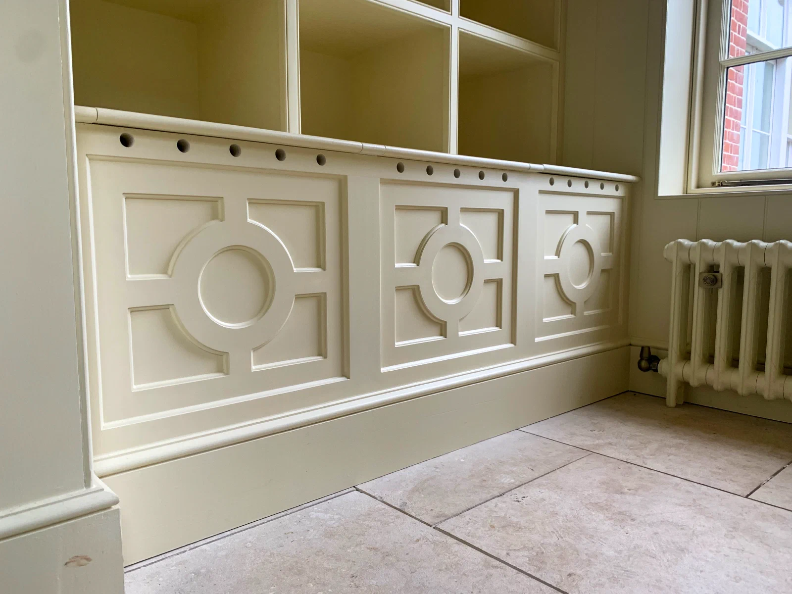 Painted panelling with a geometric circle-and-square motif beneath fitted shelving