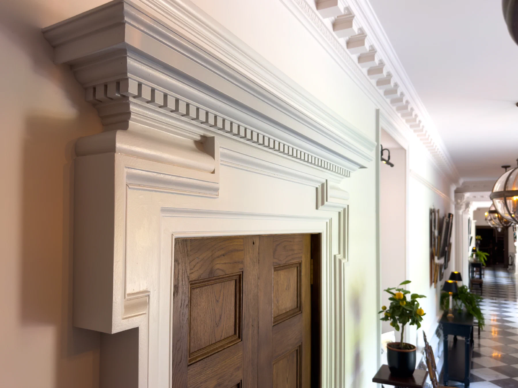 Painted door surround with a dentil cornice beside a timber door