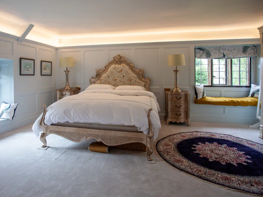 Painted panelled bedroom at Little Peacock Cottage with window seats and full-height wall panels