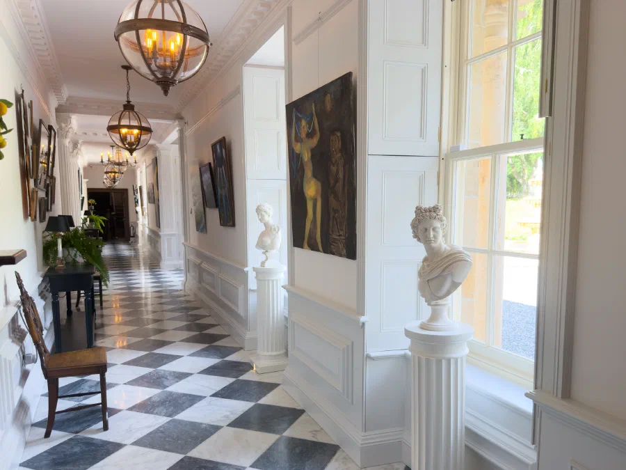 Painted panelling arranged around tall windows in a long entrance hall