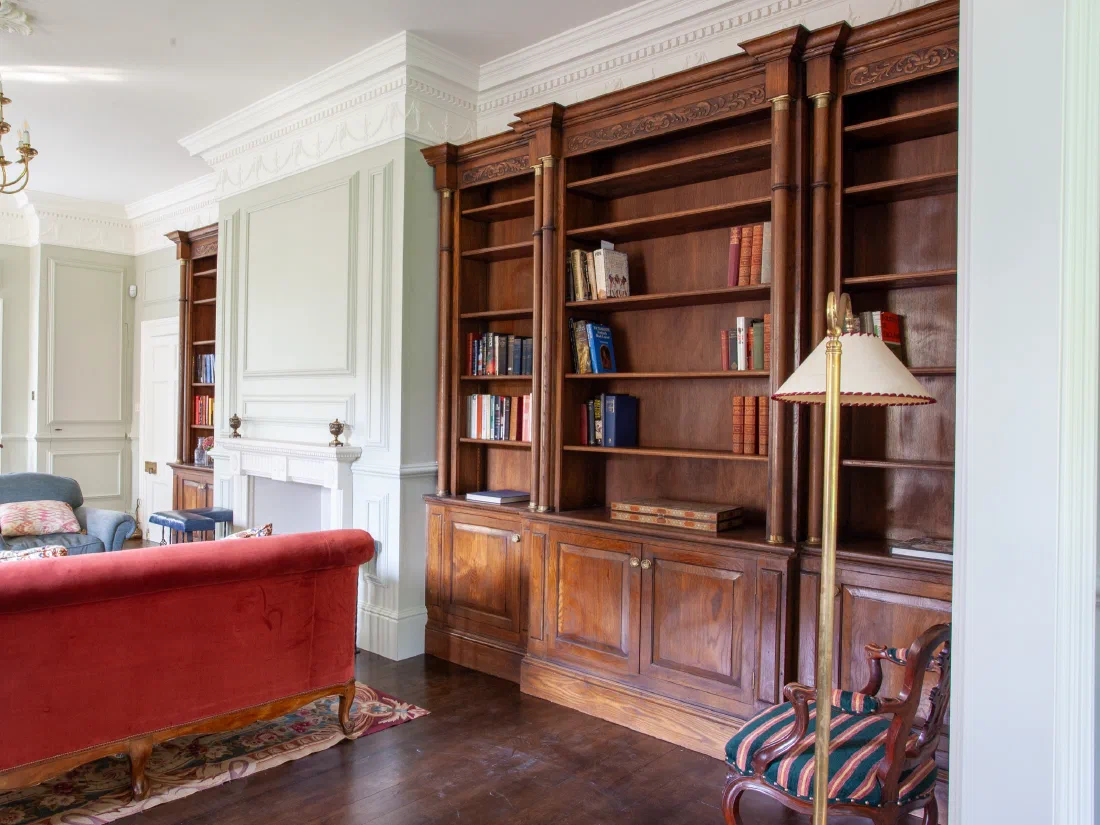 Painted panelling surrounding a fireplace with fitted oak bookcases