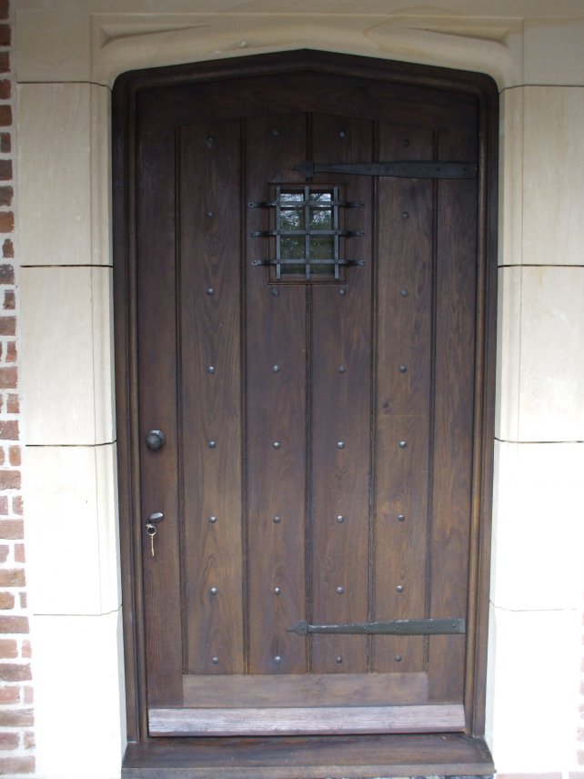 gothic top oak door and frame with iron furniture including small window and grille, faux hinges and studs