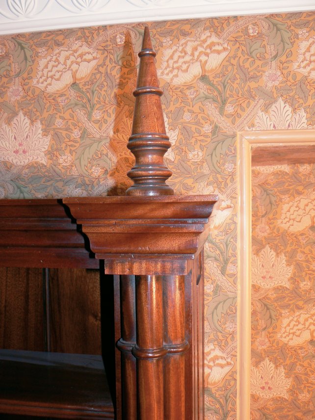 mahogany finial shown against William & Morris wallpaper