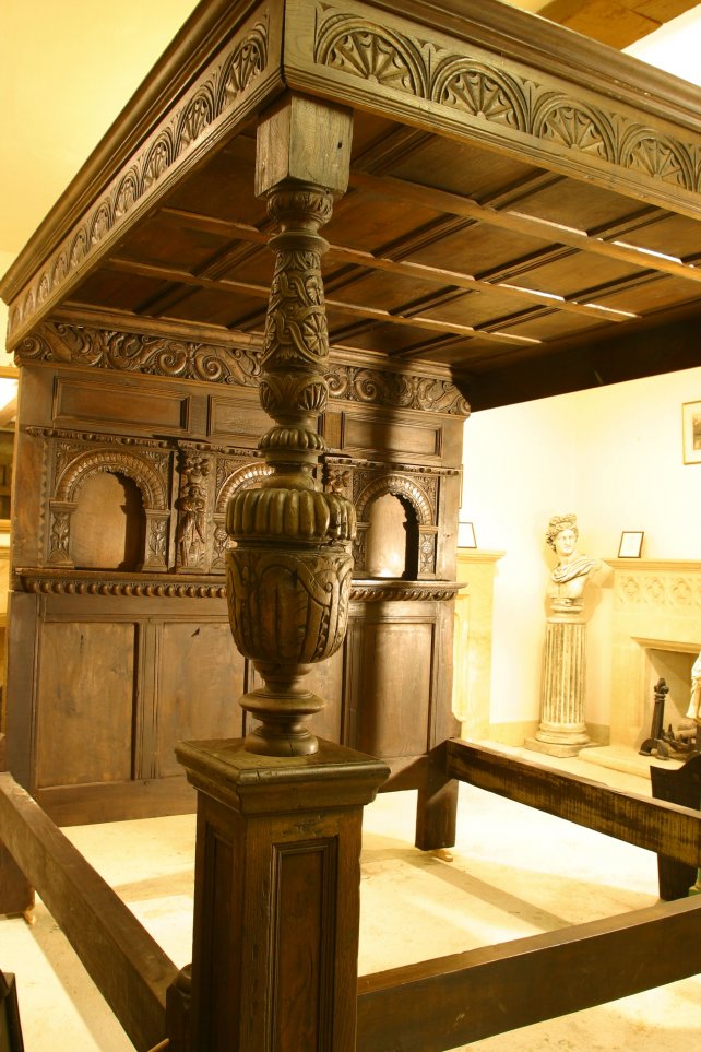 four poster bed with heavily hand carved panels and frieze and bulbous posts 