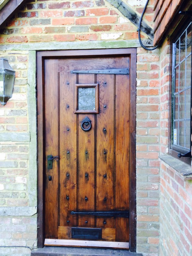 oak framed planked door with small window and handmade ironwork