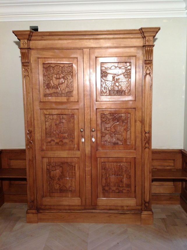 oak gun cabinet with hand carved panels depicting woodland scene