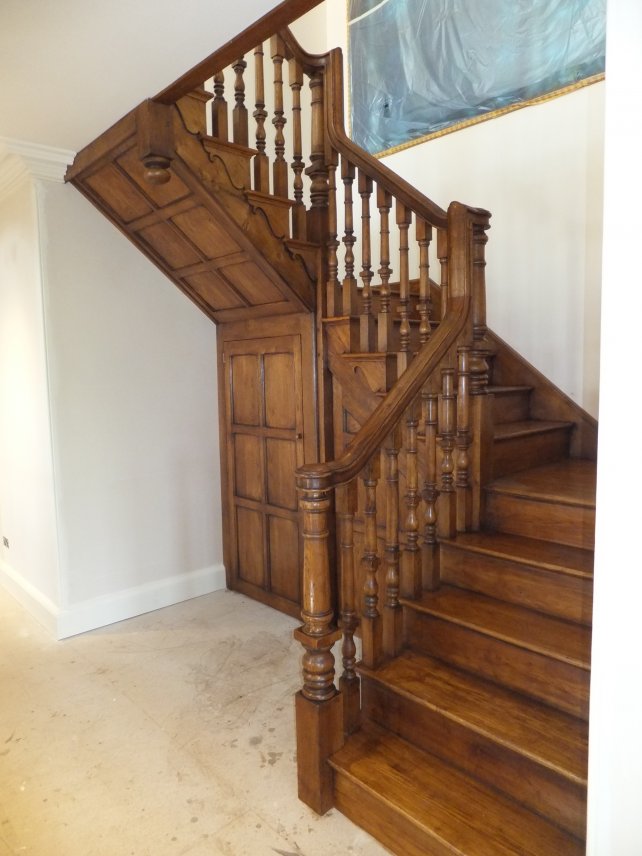 period open cut string oak staircase with carved spindles and sweeping monkey tail handrail with under stair cupboard 