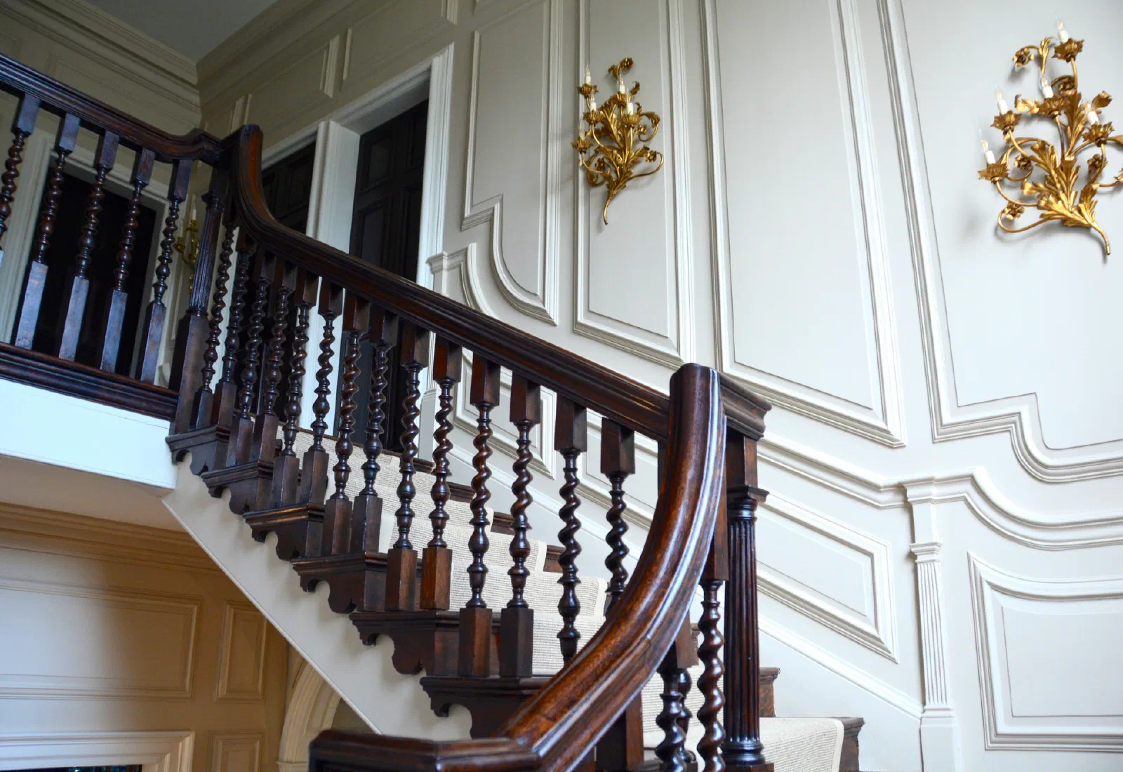 Open-string oak staircase with bracketed tread ends, slender dark balusters and a continuous curved handrail