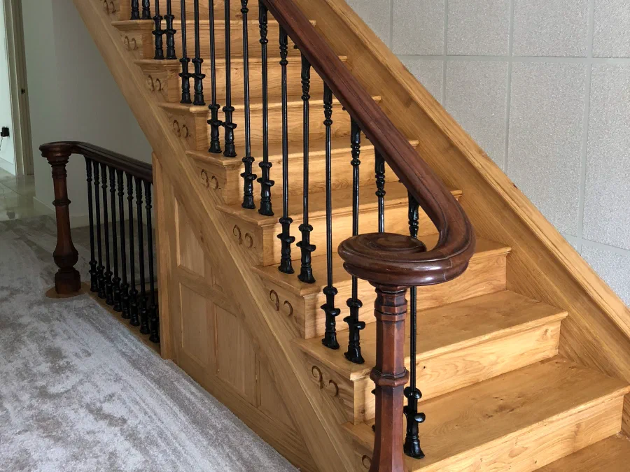 Open-string solid oak staircase with a curved handrail and dark turned balusters
