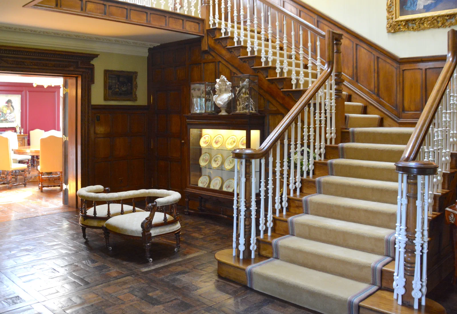 Traditional oak staircase with painted turned balusters and adjoining full-height oak panelling