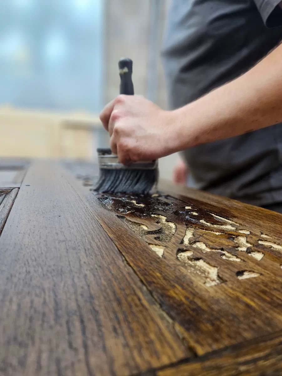 Finish being brushed onto carved oak in the workshop