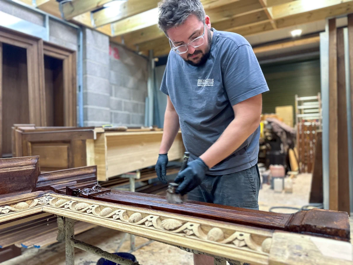 Craftsman finishing a carved oak frieze in the workshop
